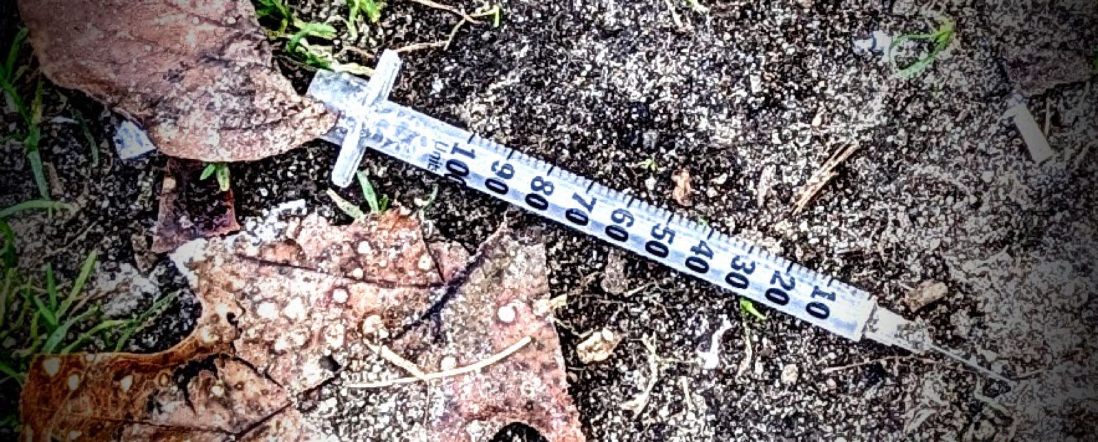 An uncapped syringe on the ground